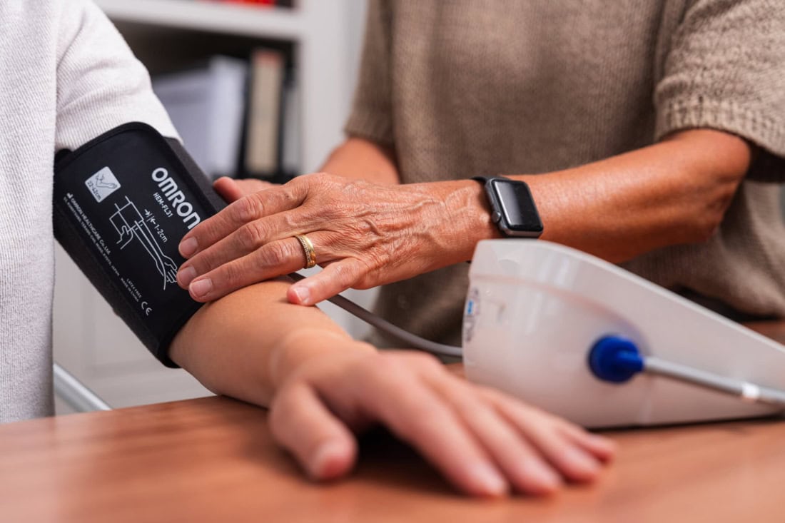 Huis bloeddruk meten met digitale bloeddrukmeter en artsassistente.