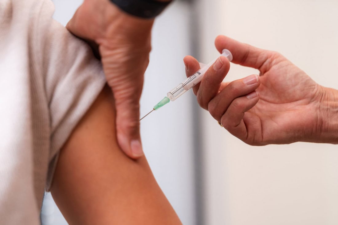 Een persoon krijgt een pneumokokkenvaccinatie toegediend in de arm.