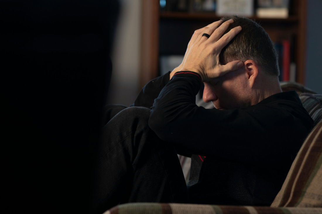 A man suffering from mental stress is holding his head in a quiet room.